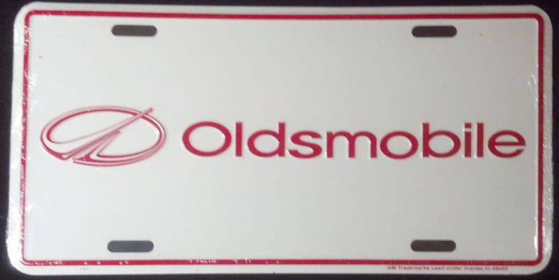 Oldsmobile embossed red on white license plate licensed by gm